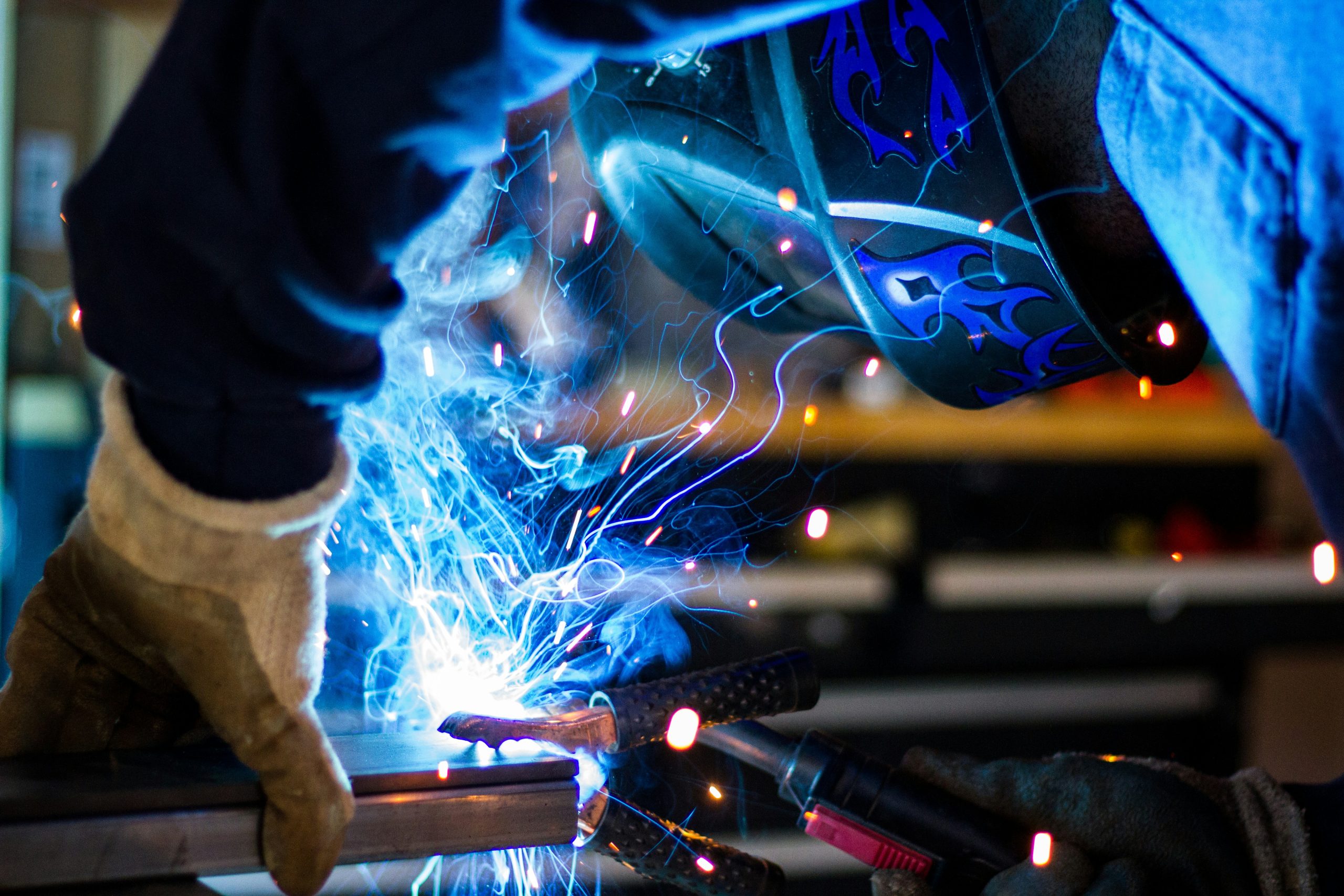 Welding process generating fumes in a school-style workshop environment demonstrating airborne contaminant risks.